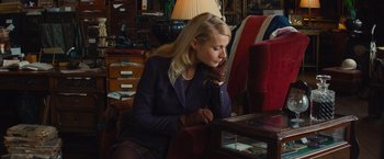 Movie still from “Mortdecai” (2015), directed by David Koepp – A woman sitting on a chair in a room; Medium shot, High angle
