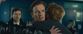 Movie still from “Mortdecai” (2015), directed by David Koepp – A man hugging another man in front of a blue wall; Close Up shot, Over the shoulder angle
