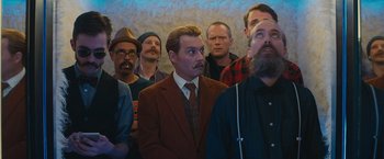 Movie still from “Mortdecai” (2015), directed by David Koepp – A group of men standing next to each other in a room; Medium shot, Low angle