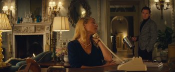 Movie still from “Mortdecai” (2015), directed by David Koepp – A woman sitting at a table talking on a phone; Medium shot, Over the shoulder angle