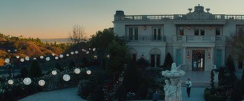 Movie still from “Mortdecai” (2015), directed by David Koepp – A large white house with a garden in front of it at dusk; Extreme Wide shot, Low angle
