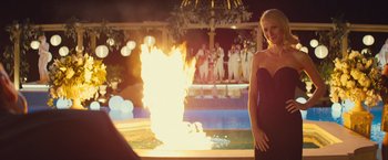 Movie still from “Mortdecai” (2015), directed by David Koepp – A woman standing next to a pool with a fire in it; Medium shot, Over the shoulder angle