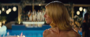 Movie still from “Mortdecai” (2015), directed by David Koepp – A woman with long blonde hair looking over her shoulder at a pool party; Close Up shot, Over the shoulder angle