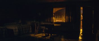 Movie still from “Mortdecai” (2015), directed by David Koepp – A dark room with a table and chairs and a window; Extreme Wide shot, Low angle