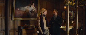 Movie still from “Mortdecai” (2015), directed by David Koepp – A man and a woman standing next to each other in a room; Medium shot, Low angle