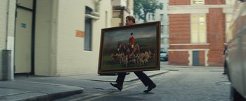 Movie still from “Mortdecai” (2015), directed by David Koepp – A man walking down the street holding a painting; Wide shot, Low angle