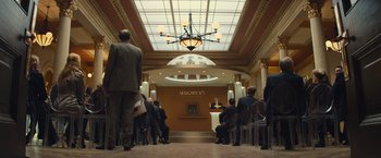 Movie still from “Mortdecai” (2015), directed by David Koepp – A group of people standing in front of a podium; Extreme Wide shot, High angle