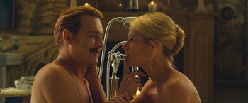 Movie still from “Mortdecai” (2015), directed by David Koepp – A man and a woman are smiling at each other in front of a bathroom mirror; Close Up shot, Low angle