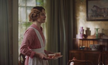 Movie still from “Mothering Sunday” (2021), directed by Eva Husson – A woman holding a tray of food in a room; Medium shot, Over the shoulder angle
