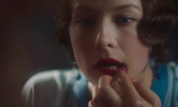 Movie still from “Mothering Sunday” (2021), directed by Eva Husson – A person with red lipstick on their lips; Extreme Close Up shot, Over the shoulder angle