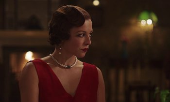 Movie still from “Mothering Sunday” (2021), directed by Eva Husson – A woman in a red dress and a pearl necklace; Close Up shot, Over the shoulder angle