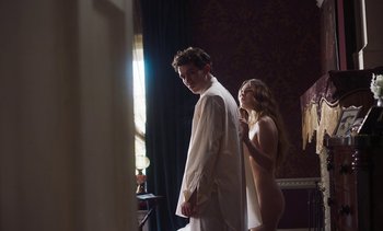 Movie still from “Mothering Sunday” (2021), directed by Eva Husson – A man and a woman standing next to each other in front of a window; Medium shot, Low angle