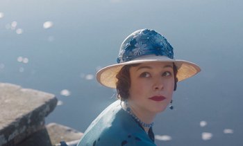 Movie still from “Mothering Sunday” (2021), directed by Eva Husson – A woman wearing a blue dress and a white hat; Close Up shot, Low angle