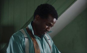 Movie still from “Mothering Sunday” (2021), directed by Eva Husson – A man in a green shirt and a brown tie; Close Up shot, Low angle