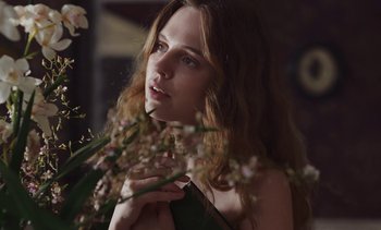 Movie still from “Mothering Sunday” (2021), directed by Eva Husson – A beautiful young lady holding a bouquet of flowers; Close Up shot, Low angle