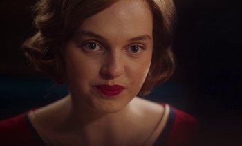 Movie still from “Mothering Sunday” (2021), directed by Eva Husson – A person wearing a red and white dress; Close Up shot, Over the shoulder angle