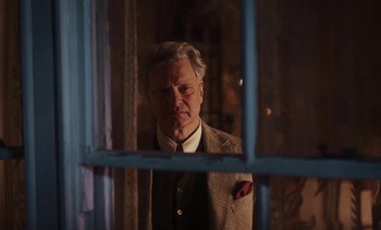Movie still from “Mothering Sunday” (2021), directed by Eva Husson – An older man wearing a suit looking out of a window; Medium shot, Low angle
