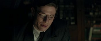 Movie still from “Mr. Jones” (2019), directed by Agnieszka Holland – A man in a suit and glasses looking down; Close Up shot, Low angle