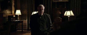 Movie still from “Mr. Jones” (2019), directed by Agnieszka Holland – An older man wearing a suit and tie in a room; Medium shot, Over the shoulder angle