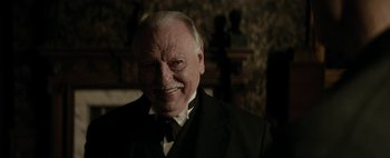 Movie still from “Mr. Jones” (2019), directed by Agnieszka Holland – An older man in a suit and tie smiling for the camera; Close Up shot, Low angle