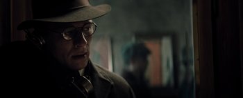 Movie still from “Mr. Jones” (2019), directed by Agnieszka Holland – A man wearing a hat and glasses in a dark room; Close Up shot, Low angle