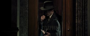 Movie still from “Mr. Jones” (2019), directed by Agnieszka Holland – A man wearing a hat and holding a notebook; Medium shot, High angle