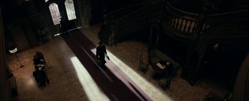 Movie still from “Mr. Jones” (2019), directed by Agnieszka Holland – Two people sitting on a red carpet in the middle of a room; Wide shot, High angle