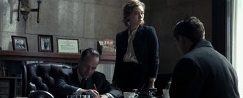 Movie still from “Mr. Jones” (2019), directed by Agnieszka Holland – A man and a woman sitting at a table in a room; Medium shot, Low angle