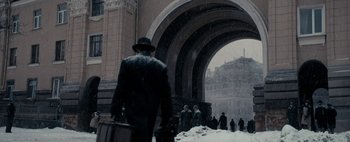 Movie still from “Mr. Jones” (2019), directed by Agnieszka Holland – A group of people standing under an archway in the snow; Wide shot, Low angle