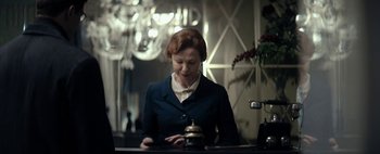 Movie still from “Mr. Jones” (2019), directed by Agnieszka Holland – A woman standing at a counter looking at a service bell; Medium shot, Low angle
