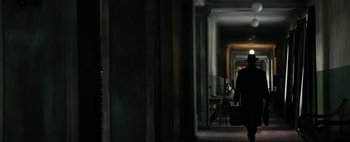 Movie still from “Mr. Jones” (2019), directed by Agnieszka Holland – A person walking down a hallway with a suitcase; Wide shot, Low angle