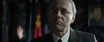 Movie still from “Mr. Jones” (2019), directed by Agnieszka Holland – An older man wearing glasses and a suit and tie; Close Up shot, Low angle