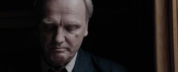 Movie still from “Mr. Jones” (2019), directed by Agnieszka Holland – An older man in a suit and tie looking sad; Close Up shot, Over the shoulder angle