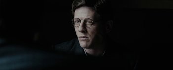 Movie still from “Mr. Jones” (2019), directed by Agnieszka Holland – A person wearing a suit and glasses; Close Up shot, Over the shoulder angle