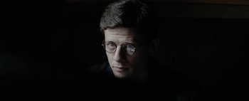 Movie still from “Mr. Jones” (2019), directed by Agnieszka Holland – A man with glasses is looking at the camera; Close Up shot, Over the shoulder angle
