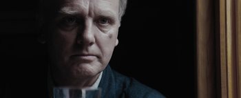 Movie still from “Mr. Jones” (2019), directed by Agnieszka Holland – An older man with a glass of wine in front of him; Close Up shot, Over the shoulder angle