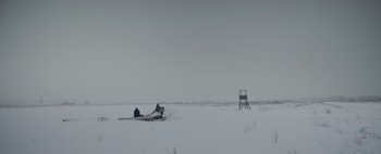 Movie still from “Mr. Jones” (2019), directed by Agnieszka Holland – A person sitting in the middle of a snowy field next to a chair; Extreme Wide shot, Low angle