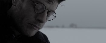 Movie still from “Mr. Jones” (2019), directed by Agnieszka Holland – A person wearing round glasses; Close Up shot, Low angle