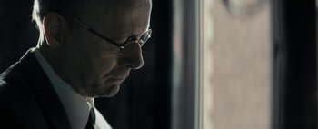 Movie still from “Mr. Jones” (2019), directed by Agnieszka Holland – A person wearing glasses near a window; Close Up shot, Low angle