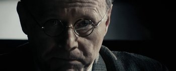 Movie still from “Mr. Jones” (2019), directed by Agnieszka Holland – An older man wearing glasses and a suit; Close Up shot, Over the shoulder angle