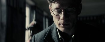 Movie still from “Mr. Jones” (2019), directed by Agnieszka Holland – A person wearing glasses and a suit; Close Up shot, Low angle