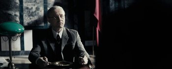Movie still from “Mr. Jones” (2019), directed by Agnieszka Holland – An older man sitting at a table in a suit and tie; Medium shot, Over the shoulder angle