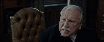 Movie still from “Mr. Jones” (2019), directed by Agnieszka Holland – An old man with a beard and mustache in a black suit; Close Up shot, Over the shoulder angle