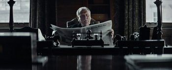 Movie still from “Mr. Jones” (2019), directed by Agnieszka Holland – An older man sitting at a desk reading a newspaper; Medium shot, Low angle