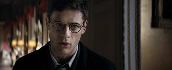 Movie still from “Mr. Jones” (2019), directed by Agnieszka Holland – A man wearing glasses and wearing a suit and tie; Close Up shot, Over the shoulder angle
