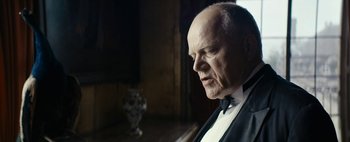 Movie still from “Mr. Jones” (2019), directed by Agnieszka Holland – An older man in a tuxedo looking out a window at an owl; Close Up shot, Over the shoulder angle