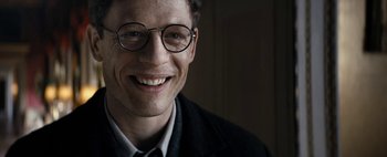 Movie still from “Mr. Jones” (2019), directed by Agnieszka Holland – A person wearing glasses and smiling; Close Up shot, Over the shoulder angle