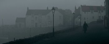 Movie still from “Mr. Jones” (2019), directed by Agnieszka Holland – A row of houses on a foggy day with street lamps; Extreme Wide shot, Low angle