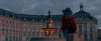 Movie still from “Mamma Mia! Here We Go Again” (2018), directed by Ol Parker – A statue of a man sitting on top of a water fountain; Extreme Wide shot, Low angle