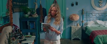 Movie still from “Mamma Mia! Here We Go Again” (2018), directed by Ol Parker – A woman standing in front of a blue wall holding an ipad; Medium shot, Over the shoulder angle
